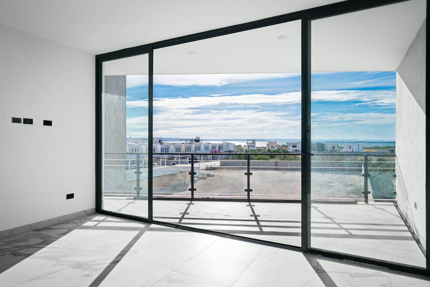 Sala con muro de cristal corredizo hacia la terraza y vista al mar